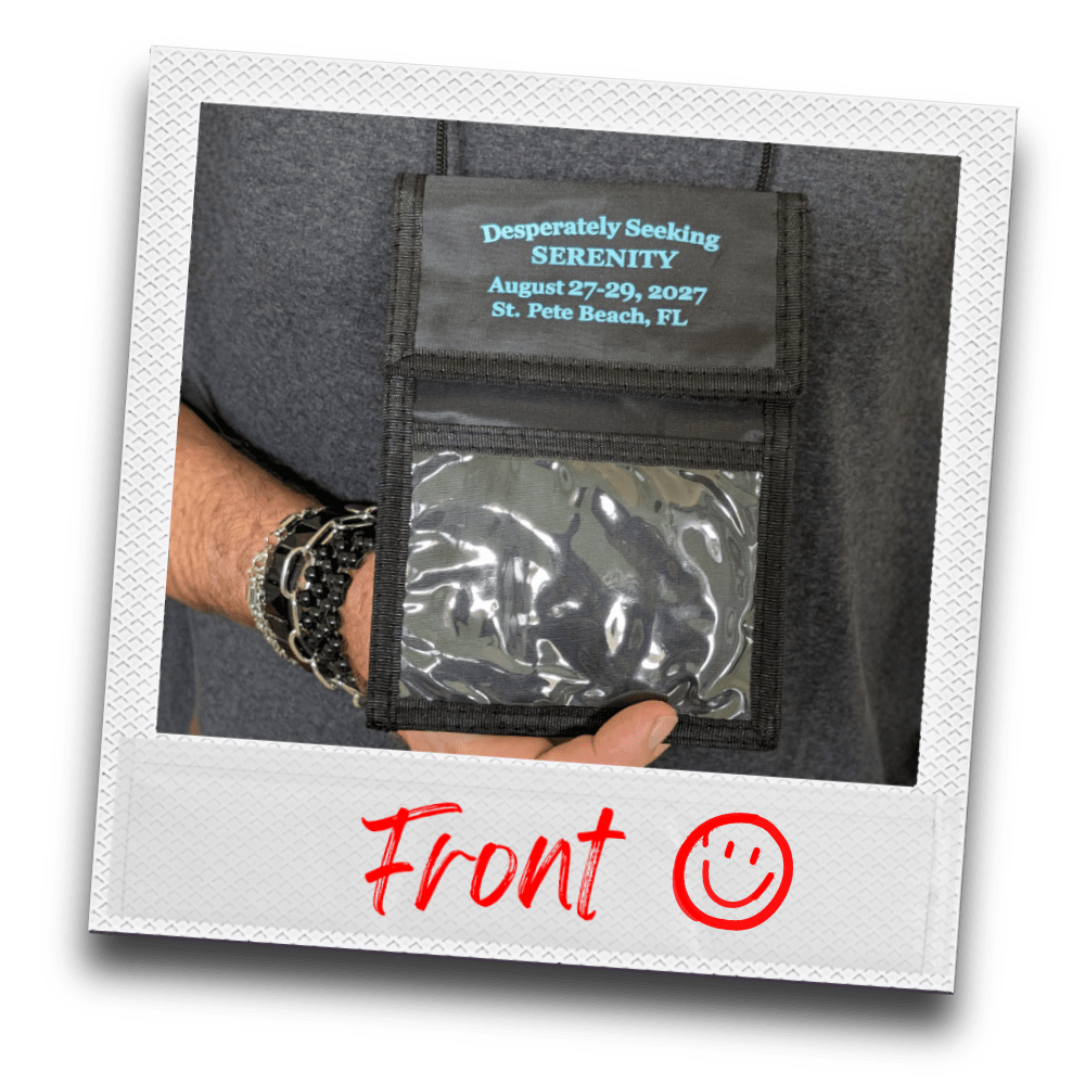 Polaroid photo of hand holding the front of a black neck wallet with clear plastic window, printed with "Desperately Seeking Serenity, August 27-29, 2027, St. Pete Beach, FL."
